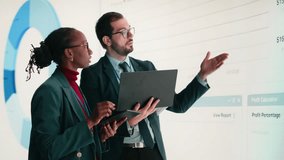 Female executive and business partner compile shareholder financial report using laptop in conference room. African american woman and coworker look at key performance indicators earnings data - Powered by Shutterstock - Get 15% off with code: PIKWIZARD15