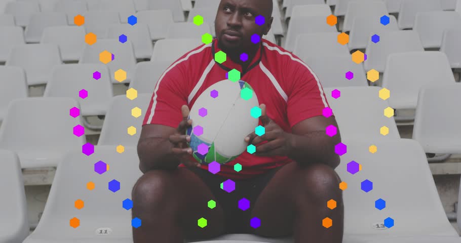 Animated hexagon overlay appearing rugby player shifting grip and rotating ball on seats for kick. Athlete, stadium, jersey, red, stand, solitary, focus