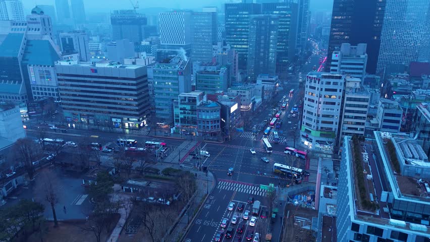 Drone aerial landscape of car vehicles and bus transport travelling through busy intersection on street surrounded by urban city building tower infrastructure in Jongo 3-ga Seoul South Korea tourism