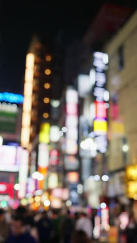 Blurred motion of people walking along vibrant neon lit streets of tokyo at night offers a lively and dynamic urban scene