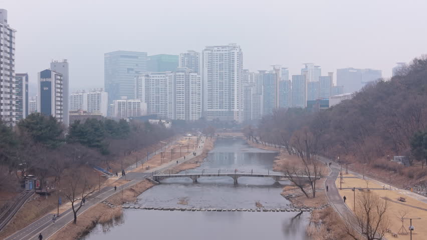 Rising drone shot over Tancheon stream in Seongnam, South Korea on a foggy winter day. Misty atmosphere with low visibility and calm riverside landscape.