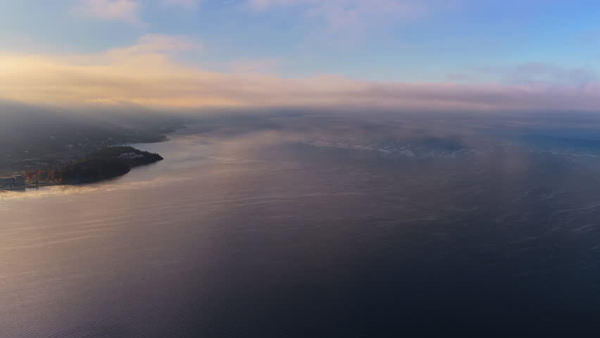 Aerial drone view of a Galichica mountain ridge rising above a sea of clouds, with soft layers of fog covering the valley below