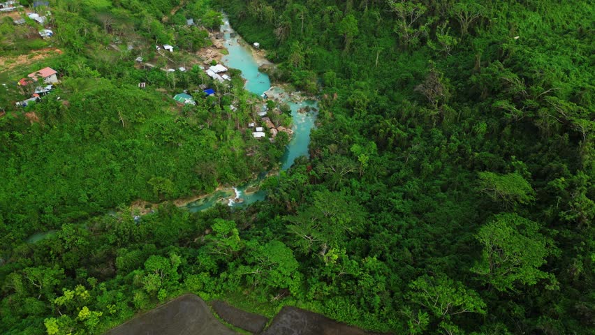 Slow downward shot highlights rushing water, textured limestone edges, and the deep blue basin surrounded by lush tropical forest at Bolinao Falls Bolinao Pangasinan Philippines