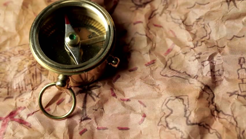Closeup of compass over stained yellowed paper sheet with part of treasure map. aged brass antique nautical compass on table with old treasure map. aged paper treasure map with compass.