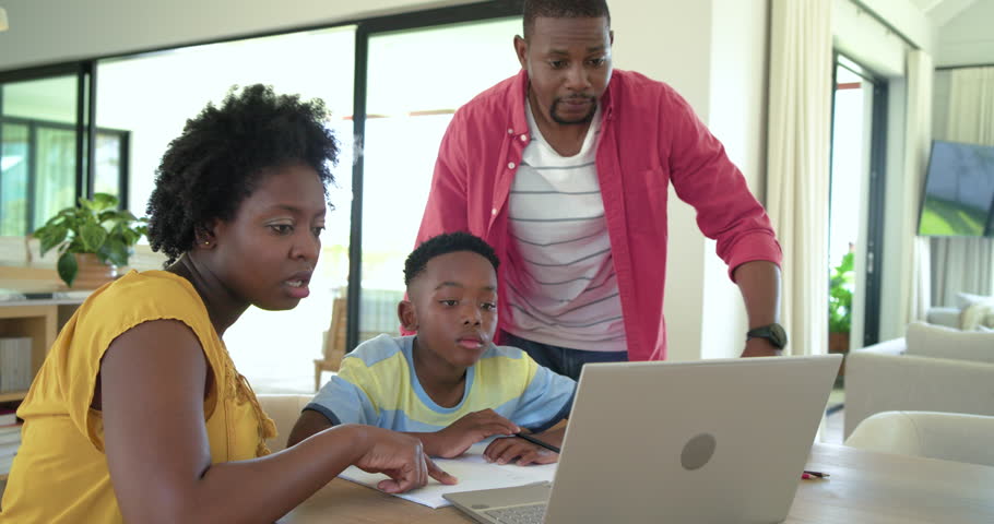 African American family mother clicking laptop guiding son studying at home and father watching. Learning, collaboration, technology, education, domestic, support, focus