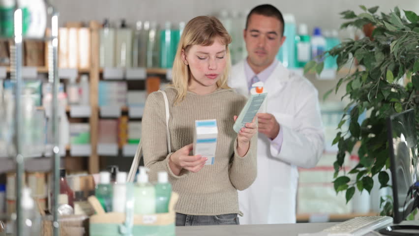 Selective young girl choosing cream while male pharmacist giving offer in chemistry