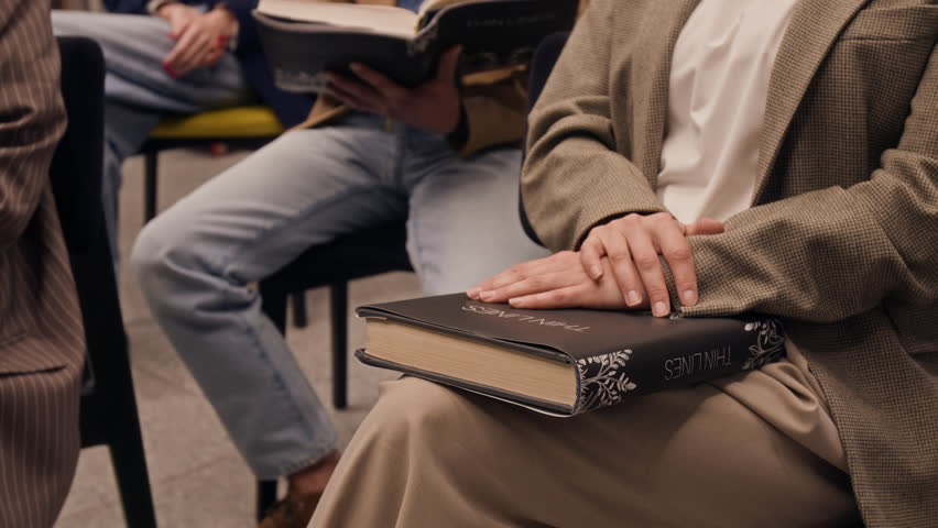 Low angle tilt-up shot of group of people laughing while listening to speaker during book club gathering in modern library