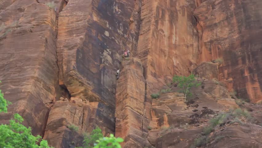 Climbers scaling a large cliff at Zion National Park in Southern Utah