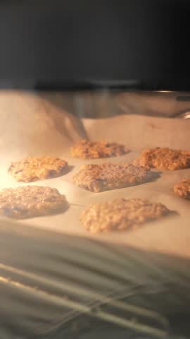 A tray of cookies is baking in an oven. The cookies are golden brown and appear to be ready to be taken out