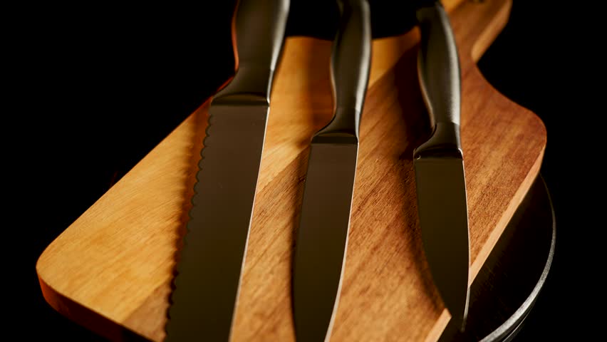 Knife set arranged on a wooden cutting board with kitchen setup in focus