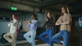 Women practicing yoga in a modern studio with large windows in the afternoon light, demonstrating tree pose for balance and focus - Powered by Shutterstock - Get 15% off with code: PIKWIZARD15