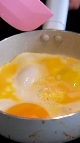 Cook prepares eggs on frying pan. Chef repeat omelet, close-up.