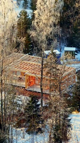 Timber Frame Building Under Construction In The Rural Area In Winter. - aerial vertical shot