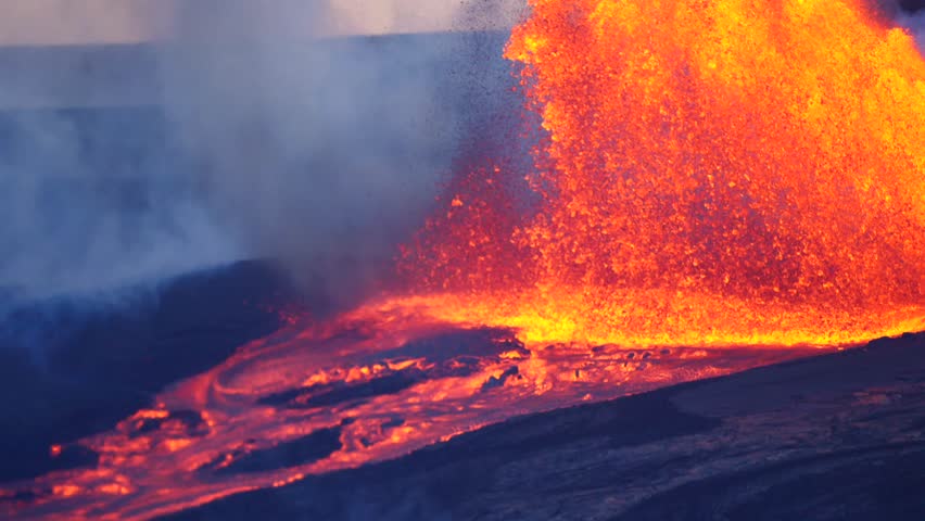 Close up slow motion footage of molten lava erupting violently into the air and flowing down from an active volcano.