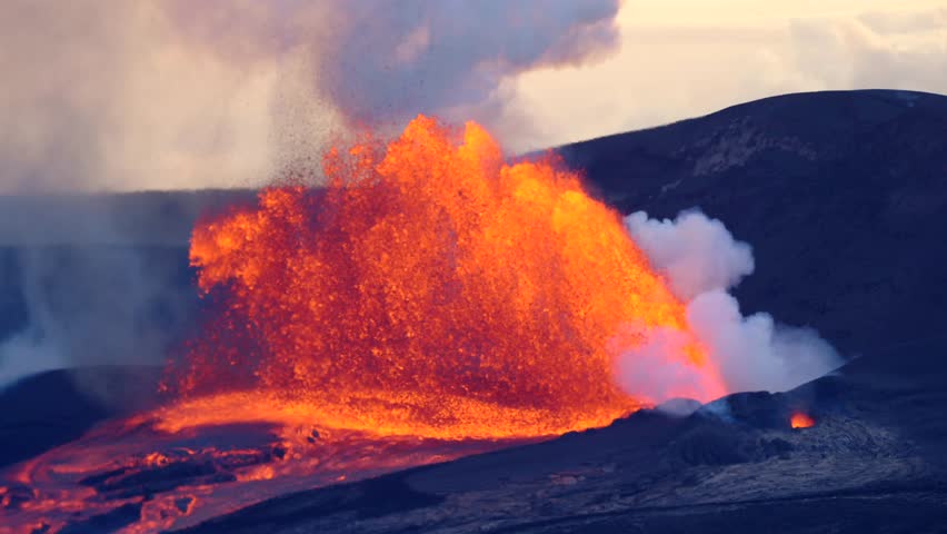 Slow-motion footage of a Hawaiian volcano erupting, molten lava blasting high into the sky as glowing fire and ash light up the landscape in a dramatic natural spectacle.