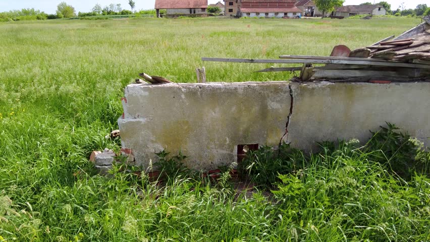 The soccer field is abandoned and overgrown with weeds. Damaged benches for referees and reserve players.