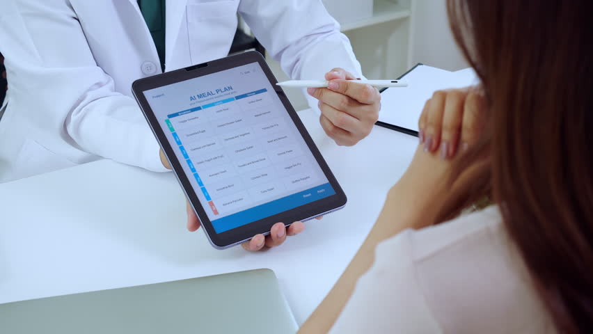 Asian nutritionist using tablet to explaining personalized meal plan with AI to patient during healthcare consultation, healthy lifestyle, man dietitian showing nutrition plan with AI on tablet.