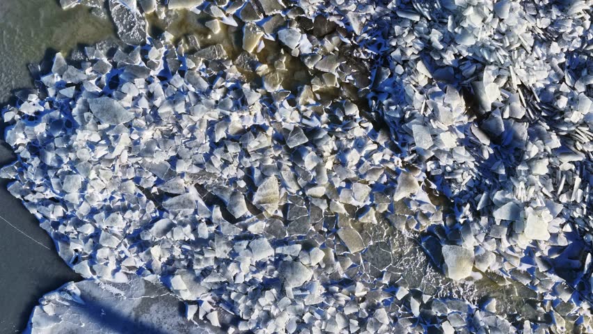 Broken ice sheets on frozen water, creating intricate cold patterns and abstract shapes