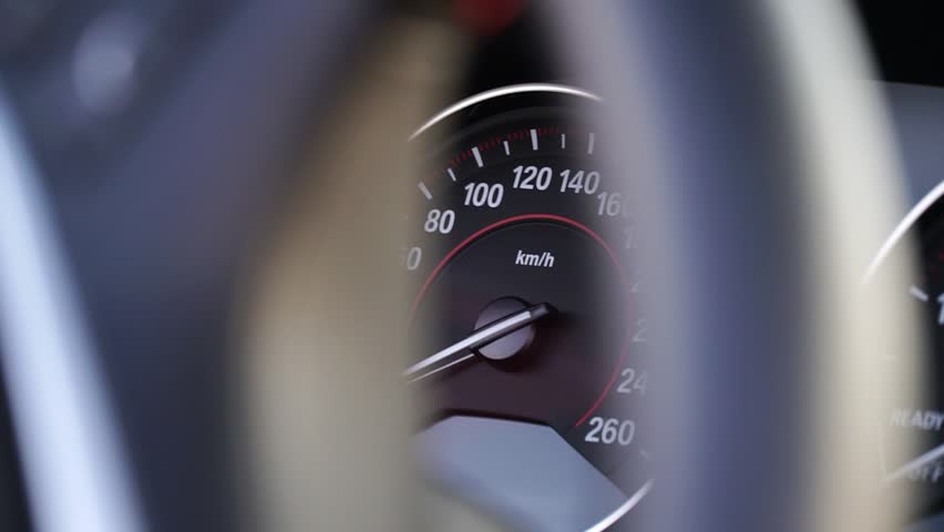 Speedometer gauge displaying increasing velocity, with needle moving from 60 to 100 km h, framed by steering wheel, capturing dynamic driving experience and vehicle performance in motion