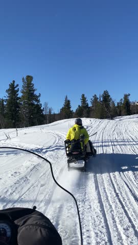 Snowmobile in ski resort. Vertical first-person video of a snowmobile ride through snowy terrain with fir trees in the Sheregesh mountains