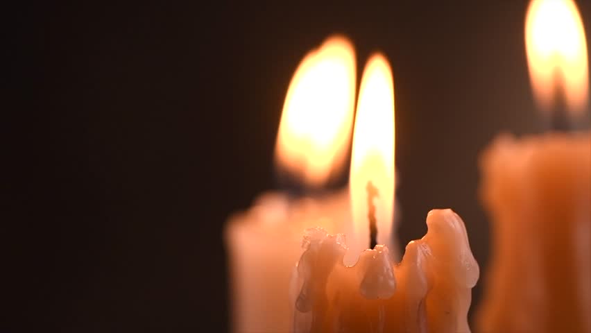 Candles flame close up on a dark background. Candle light border design. Melted wax candle burning at night. White Candles Burning in the dark. Flame, Candlelight. Religion theme. Slow motion.