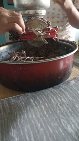 Close-up of grinding beans in a red manual mill