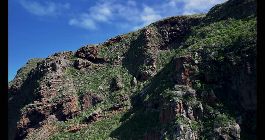 Panoramic view of green mountains and rugged cliffs on Tenerife Island in sunny Spain