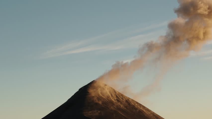 Ash plume drifting from Fuego Volcano crater at sunsetc