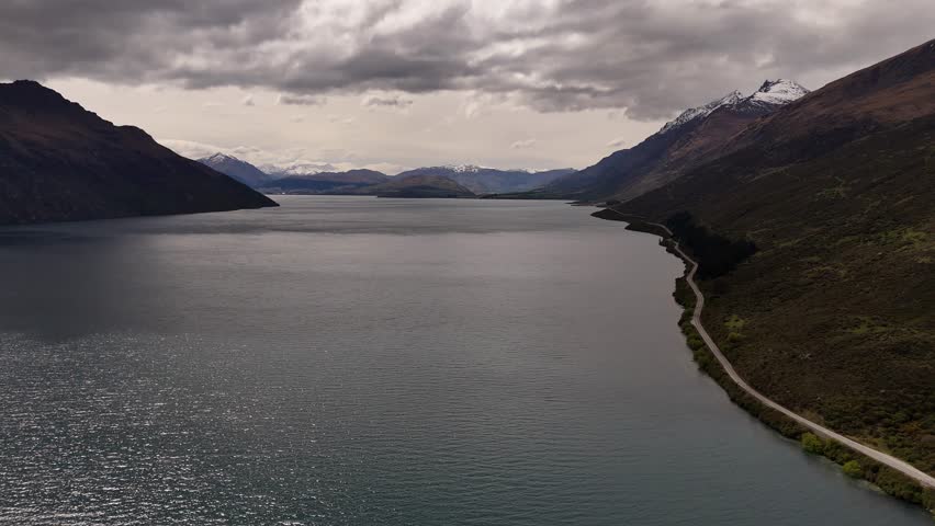 Aerial view of Lake Wakatipu and the mountains of New Zealands South island under a cloudy sky.