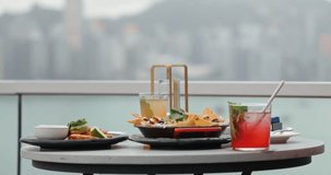Mexican appetizers and cocktails sitting on rooftop table against city skyline with hand holding glass. luxury travel, urban lifestyle, gourmet dining, social gathering, vacation vibes. - Powered by Shutterstock - Get 15% off with code: PIKWIZARD15