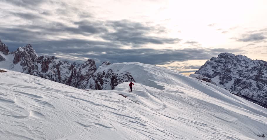 Aerial footage of a ski mountaineer in a snowy alpine ridge in Dolomites. Winter landscape, backcountry adventure, and solitude in breathtaking mountain scenery captured in 4K.