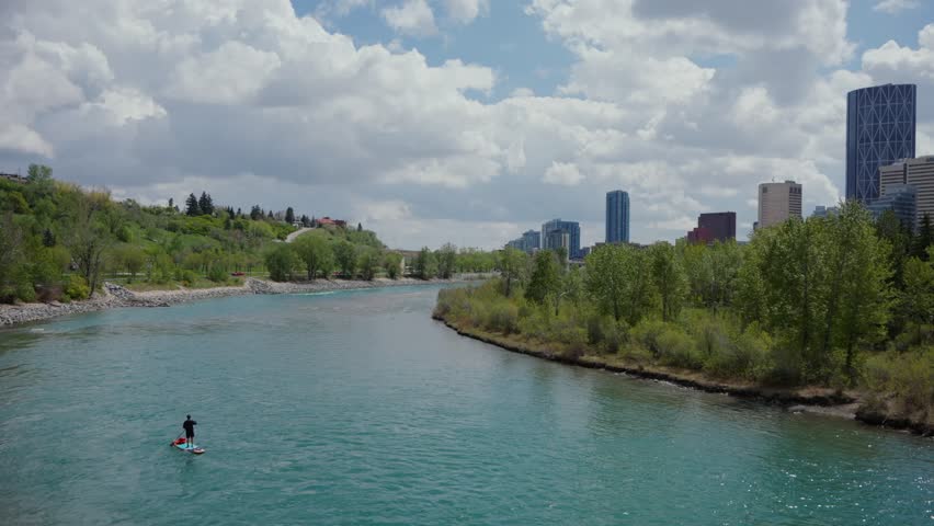 Paddleboarder enjoying the outdoors on Bow River with the city skyline in Calgary, Alberta