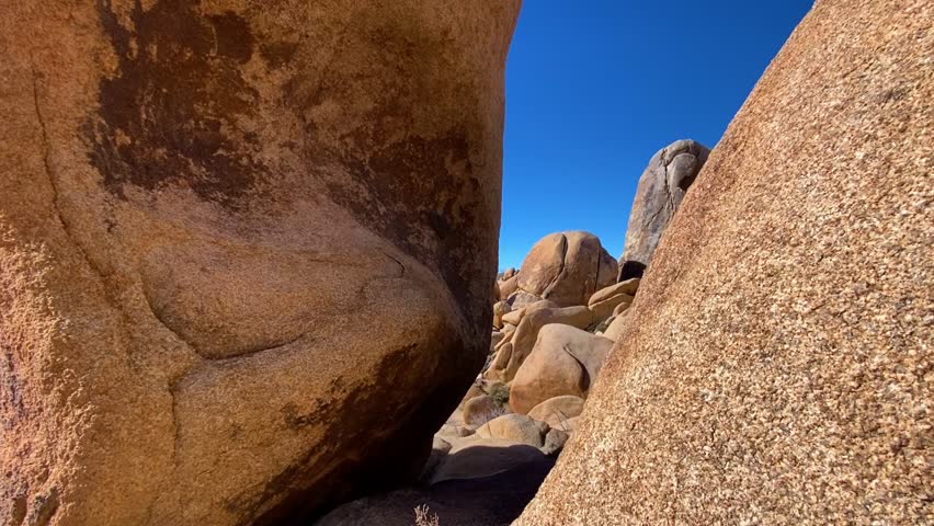🏜️ Desert Wonders: Scenic Rock Formations in Joshua Tree. Smooth cinematic reveal of unique rounded rock formations and boulders in Joshua Tree National Park. Desert vegetation under a bright sun and blue sky. Atmosphere of unforgettable adventure.