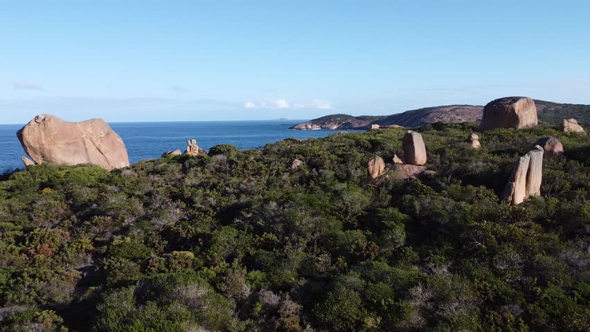 Cinematic drone footage over Hellfire Bay in Cape Le Grand National Park, Western Australia, showcasing vivid turquoise water, pristine white sand and granite rock formations along the curved shoreline of this iconic Australian beach.