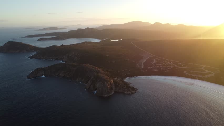 Wide aerial drone shot tracking left along the coastline of Lucky Bay in Cape Le Grand National Park, Western Australia. Smooth lateral movement showcasing turquoise waters, brilliant white sand and the expansive Australian shoreline from a distant panoramic perspective.