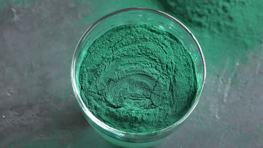 Stirring green spirulina algae powder in a glass of water