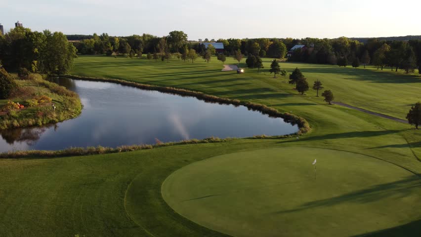 Aerial of Green Bay Wisconsin Golf Course on an evening night.  High drone shot tracking golf cart.