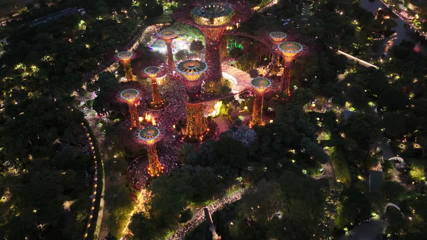 Singapore by Night – 4K aerial drone footage of marina bay sands, city skyline, skyscrapers, gardens by the bay, garden Rhapsody, dome and river illuminated in financial district.