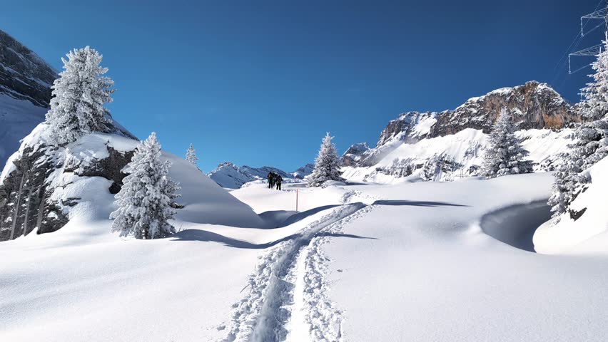 People walking up the snowshoe trail in Swiss winter alpine mountain landscape