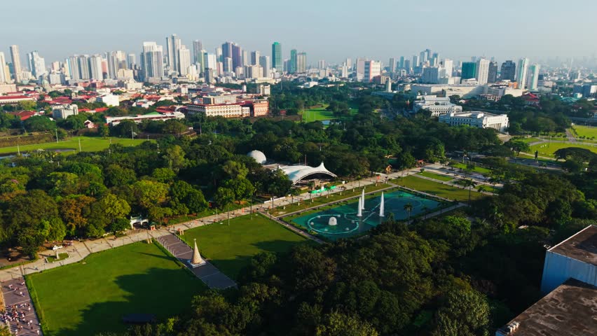 Lush Rizal Park lawns and fountains beneath Manila skyline at dawn