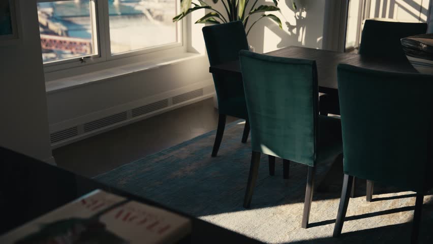 Sunlight enters a modern dining room as shades rise, revealing chairs, table, and shadows moving across the floor