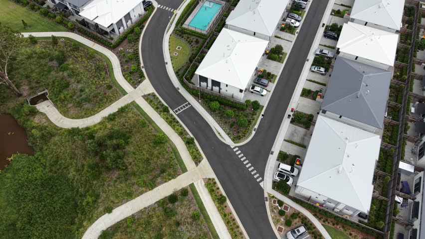 Modern Australian suburban neighbourhood with new houses, streets, and a community swimming pool seen from an aerial perspective, showing contemporary residential development and planning