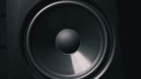 Extreme close-up of a black speaker woofer cone vibrating with low frequency bass. The membrane moves back and forth in a dark environment creating powerful audio waves. - Powered by Shutterstock - Get 15% off with code: PIKWIZARD15