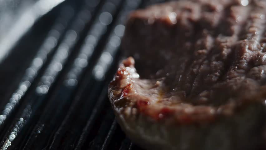 Close-up of a delicious steak sizzling on a grill, showcasing its rich texture and golden-brown sear. Perfect for food and cooking content in high definition quality.
