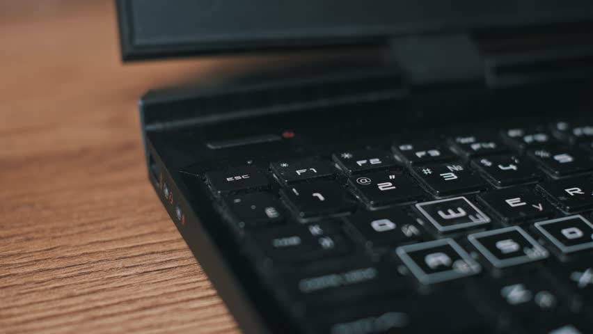 Close-up of a finger pressing the escape key on a dusty black laptop keyboard. The visual emphasizes the need for computer maintenance while depicting an action of quitting or cancelling.
