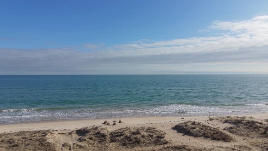 Beautiful coastal landscape with turquoise sea and sandy beach under bright sky.