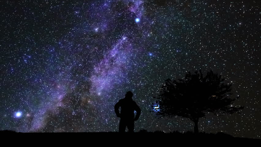 Silhouette of a man and countryside under the Milky Way stars.