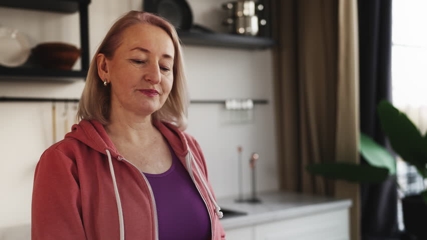 Middle-aged woman in activewear drinking green smoothie, superfood cocktail