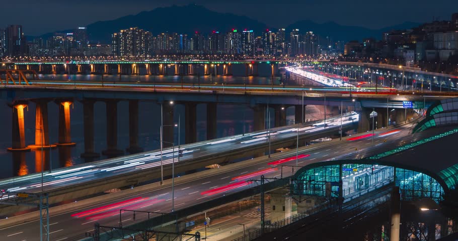 Seoul, South Korea - night time lapse, traffic light trails on Gangbyeonbuk-ro expressway, subway train arriving Oksu Station, illuminated Donho Bridge, Hannam Bridge reflecting on Han River, glowing