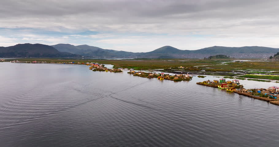 Traditional totora reed islands and homes of the Uru people on Lake Titicaca in Puno, Peru. Aerial drone ascending, copy space